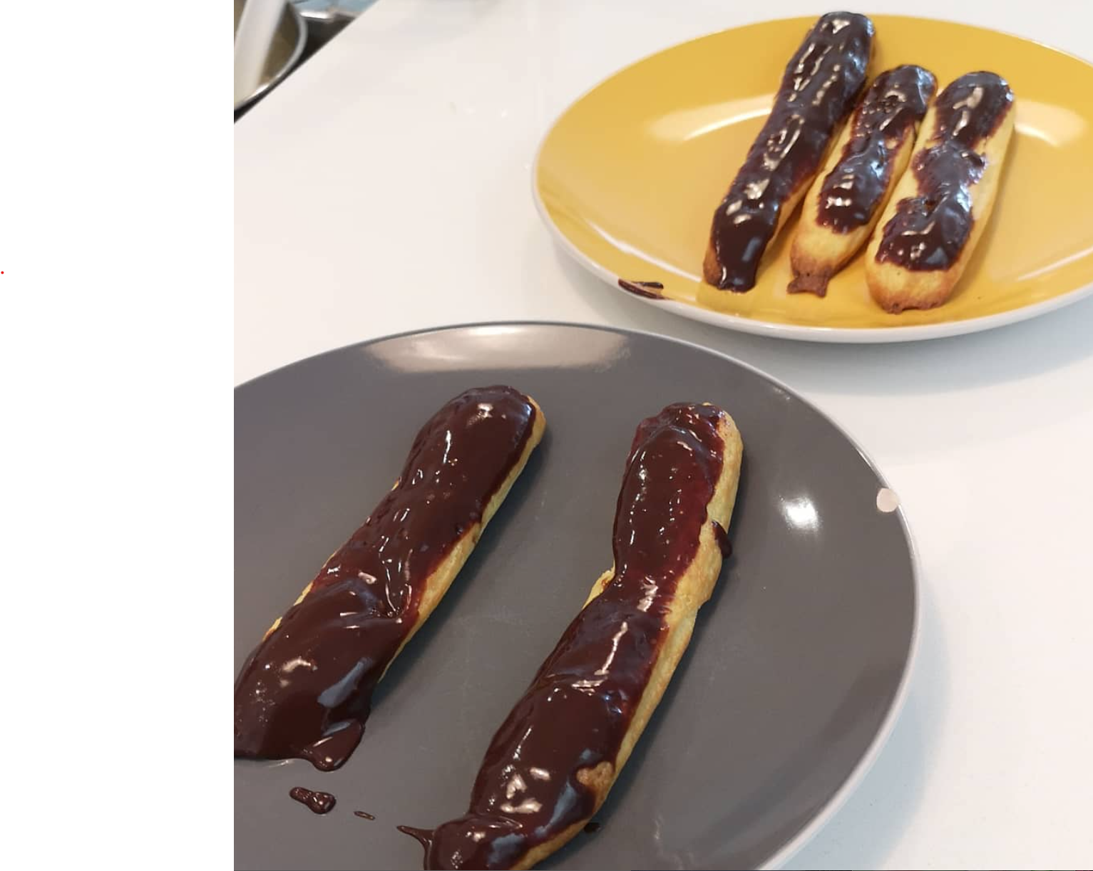 Deflated, finger-like eclairs on a baking sheet.